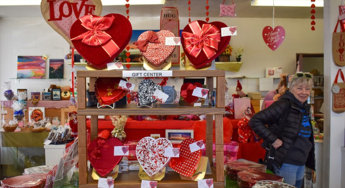 A customer waits for her order in the storefront of Johnson Candy Company. The store is decked out in red and pink decorations and heart-shaped boxes of chocolate for Valentine's Day. (Credit: Lauren Gallup / NWPB)