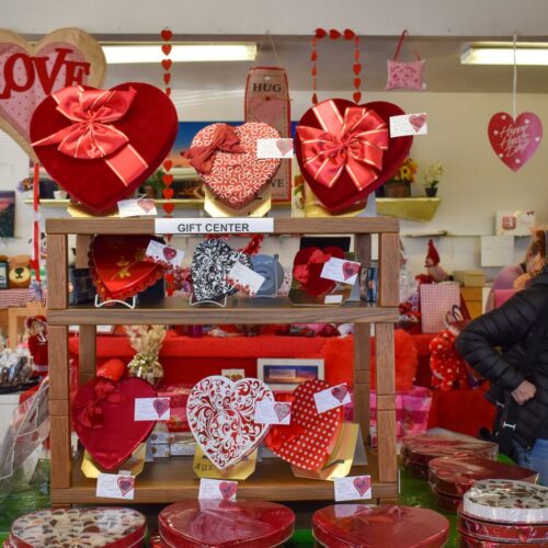 A customer waits for her order in the storefront of Johnson Candy Company. The store is decked out in red and pink decorations and heart-shaped boxes of chocolate for Valentine's Day. (Credit: Lauren Gallup / NWPB)