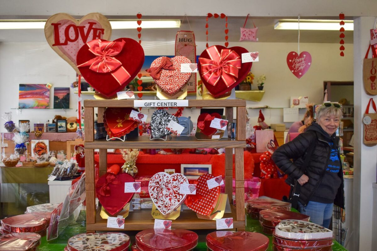 A customer waits for her order in the storefront of Johnson Candy Company. The store is decked out in red and pink decorations and heart-shaped boxes of chocolate for Valentine's Day. (Credit: Lauren Gallup / NWPB)