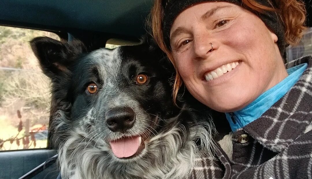 A person poses for a selfie with their dog. The person is smiling.