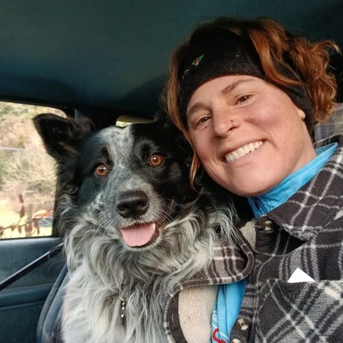 A person poses for a selfie with their dog. The person is smiling.