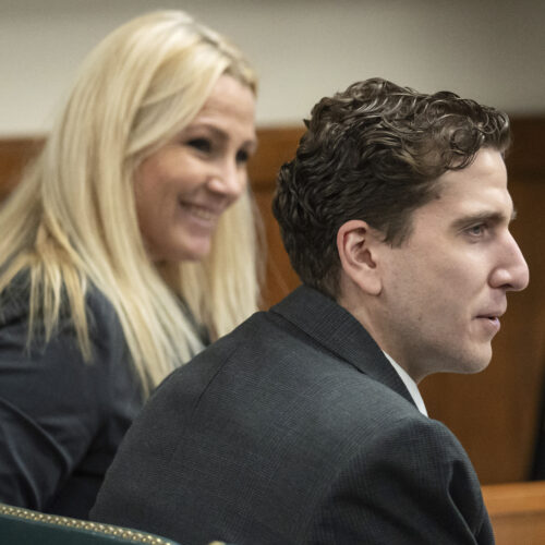 Bryan Kohberger wears a grey suit and sits next to his attorney Anne Taylor, who also wears a grey suit and has blonde hair, in a Latah County Courtroom.