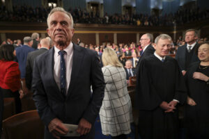 Robert F. Kennedy Jr. stands inside the Capitol building. Members of Congress stand behind him.