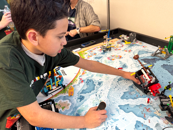 Fourth grader Sergio Preciado shows off a Lego shipwreck he helped build and code with his FIRST Lego League team, called the Dino Nuggys. The program is mostly grant funded through the Washington Office of Superintendent of Public Instruction. (Credit: Courtney Flatt / NWPB)