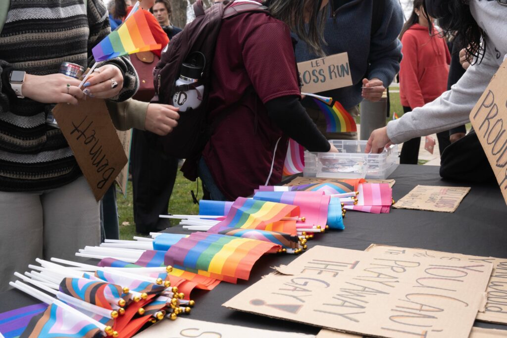 A table covered with rainbow flags and cardboard signs.